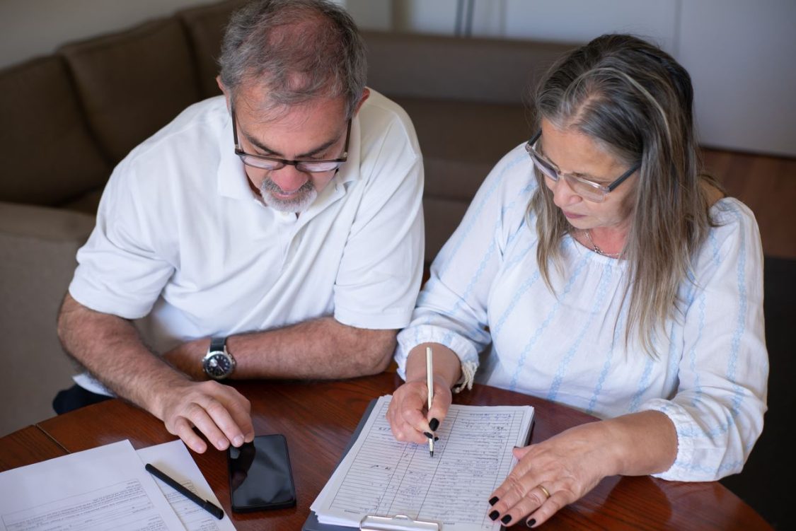 a family sitting at a table reviewing bills and budgeting documents, reflecting financial stress and planning